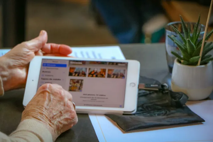 Ältere Hände bedienen ein Tablet auf einem Tisch